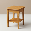 Teak wood side table with lower shelf on a neutral background